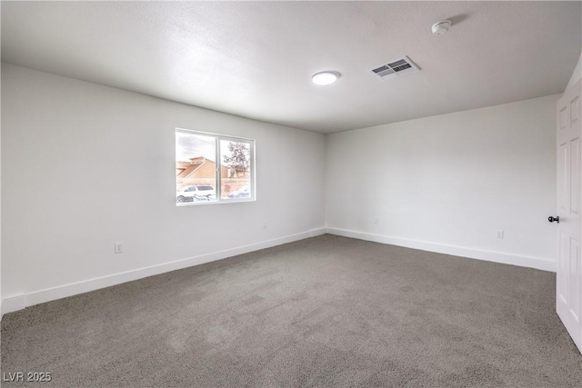 unfurnished room with visible vents, baseboards, and dark carpet