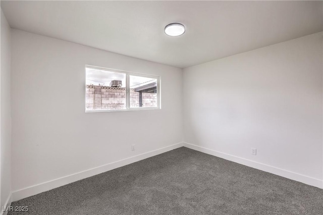 empty room featuring baseboards and dark colored carpet