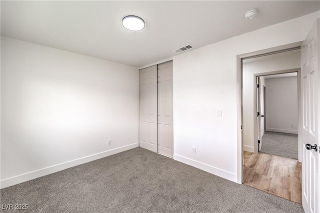 unfurnished bedroom with a closet, visible vents, baseboards, and carpet floors