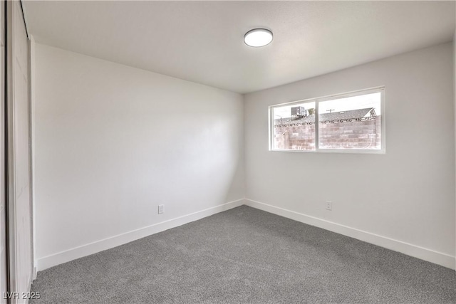 unfurnished room featuring dark carpet and baseboards