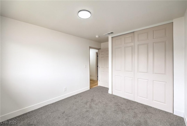 unfurnished bedroom featuring a closet, visible vents, baseboards, and carpet floors