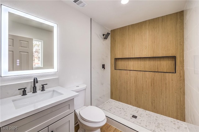 full bath featuring visible vents, tiled shower, toilet, and vanity