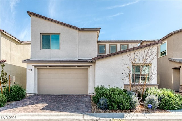 multi unit property with stucco siding, a tile roof, decorative driveway, and a garage