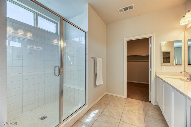 bathroom with a spacious closet, visible vents, a stall shower, tile patterned floors, and vanity