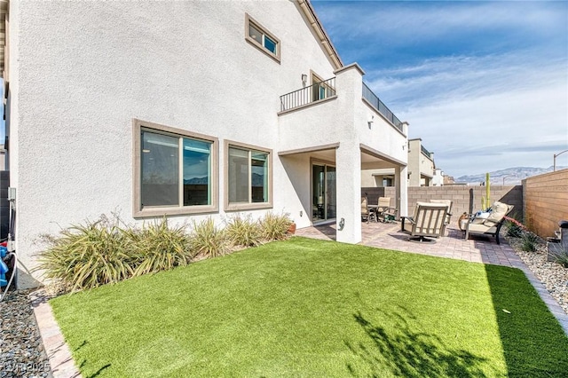 exterior space with a balcony, a patio area, a fenced backyard, and stucco siding