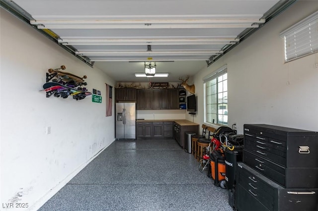 garage featuring a garage door opener and stainless steel fridge with ice dispenser