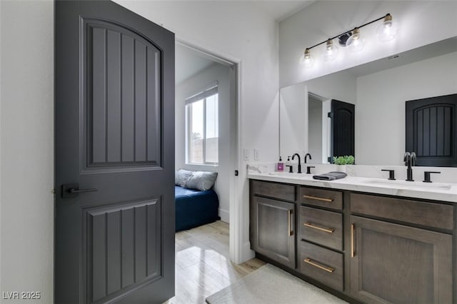 full bath with double vanity, wood finished floors, and a sink