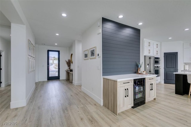 entryway with wine cooler, recessed lighting, light wood-style flooring, and baseboards