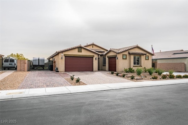 view of front of house featuring stucco siding, an attached garage, a tile roof, and a gate