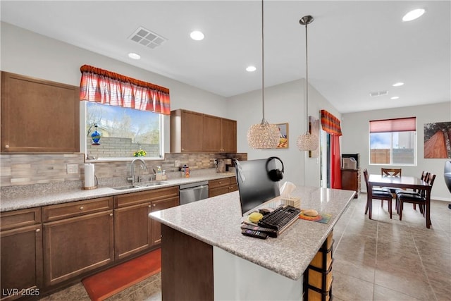 kitchen featuring visible vents, backsplash, a kitchen bar, stainless steel dishwasher, and a sink