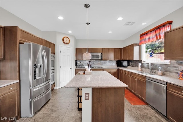 kitchen featuring visible vents, a center island, decorative backsplash, stainless steel appliances, and a sink