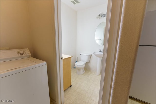 laundry area with visible vents, baseboards, light floors, laundry area, and washer / dryer