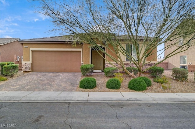 view of front facade with stone siding, stucco siding, decorative driveway, and a garage