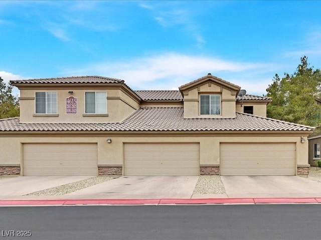 mediterranean / spanish-style house with stucco siding, stone siding, concrete driveway, and a tile roof