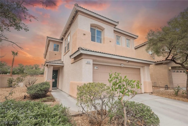 mediterranean / spanish-style house with a tile roof, stucco siding, and concrete driveway