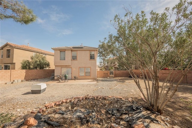 back of property with a patio area, roof mounted solar panels, stucco siding, and a fenced backyard