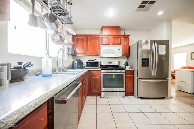 kitchen featuring visible vents, light tile patterned flooring, a sink, stainless steel appliances, and light countertops