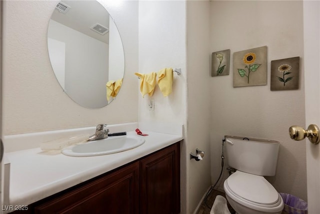 bathroom featuring visible vents, toilet, and vanity