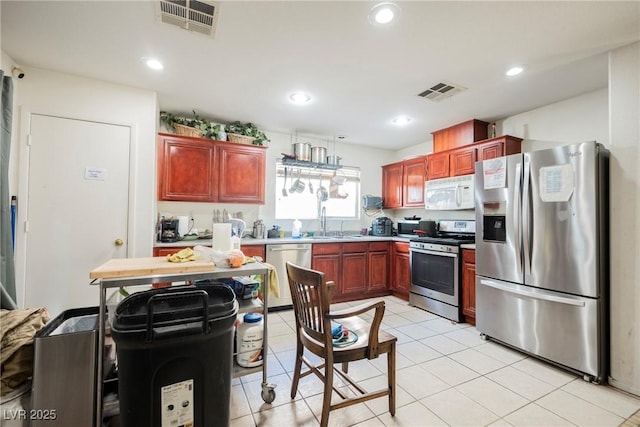 kitchen featuring light tile patterned flooring, visible vents, appliances with stainless steel finishes, and a sink