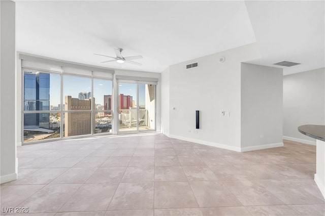 spare room featuring baseboards, visible vents, a city view, and ceiling fan