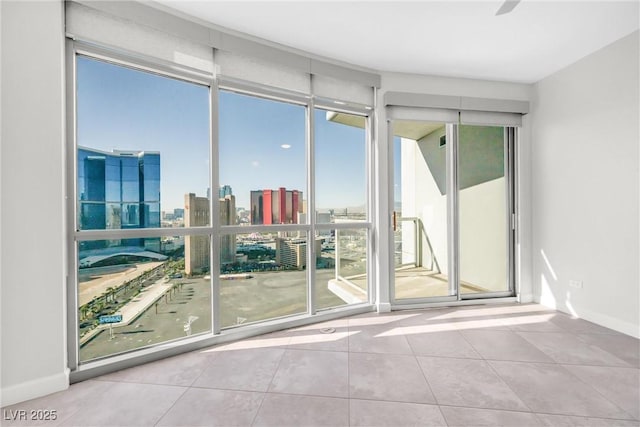 spare room with a city view, baseboards, and tile patterned flooring