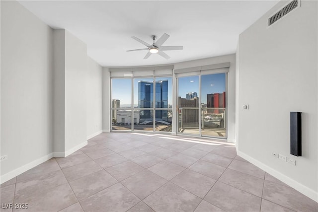 tiled spare room featuring visible vents, a view of city, baseboards, and a ceiling fan