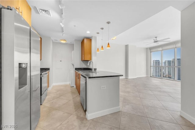 kitchen with visible vents, a sink, dark countertops, appliances with stainless steel finishes, and a peninsula