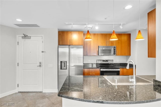 kitchen with visible vents, decorative light fixtures, dark stone countertops, stainless steel appliances, and brown cabinetry