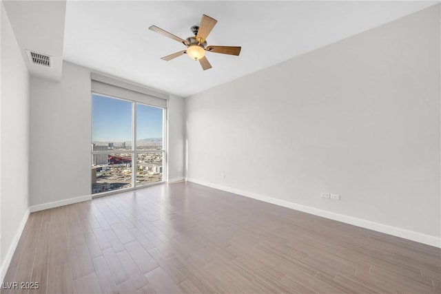 spare room featuring visible vents, baseboards, a ceiling fan, and wood finished floors