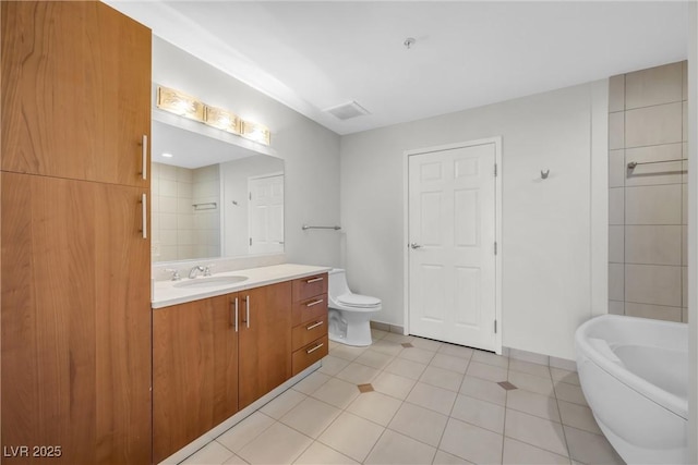 full bathroom featuring vanity, baseboards, a freestanding bath, tile patterned floors, and toilet