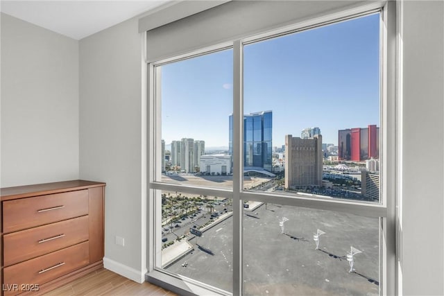 unfurnished bedroom with a city view, wood finished floors, and baseboards