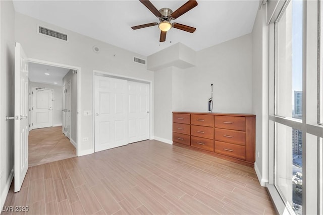 unfurnished bedroom featuring visible vents, multiple windows, and light wood-style floors