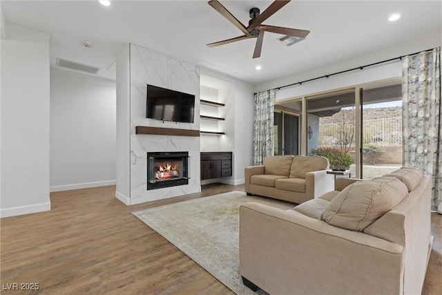 living room featuring visible vents, wood finished floors, recessed lighting, a premium fireplace, and baseboards