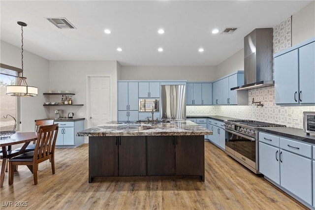 kitchen with visible vents, appliances with stainless steel finishes, light wood-type flooring, and wall chimney exhaust hood