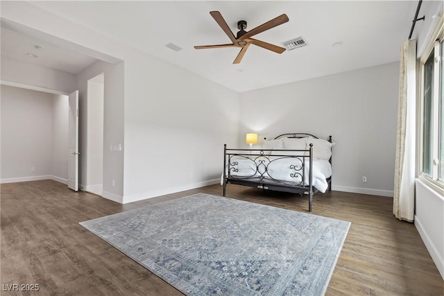 bedroom featuring visible vents, baseboards, wood finished floors, and a ceiling fan