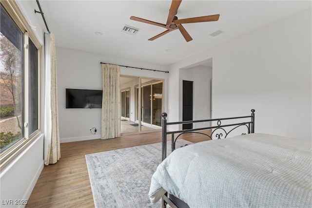 bedroom with multiple windows, wood finished floors, visible vents, and baseboards