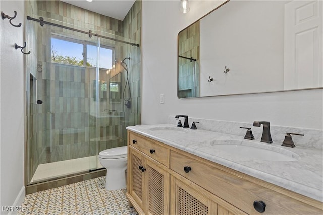 full bath featuring double vanity, a shower stall, toilet, and a sink