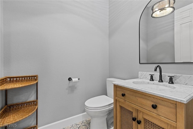 bathroom with toilet, vanity, and baseboards