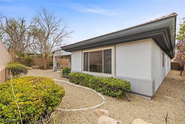 view of side of home featuring stucco siding and a fenced backyard