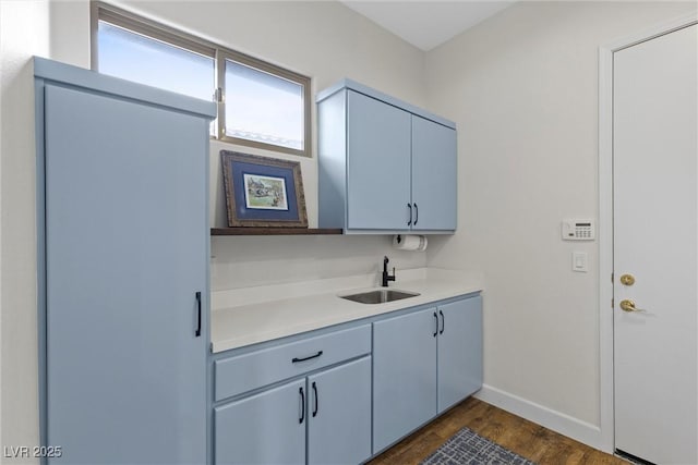 kitchen featuring a sink, baseboards, dark wood finished floors, and light countertops