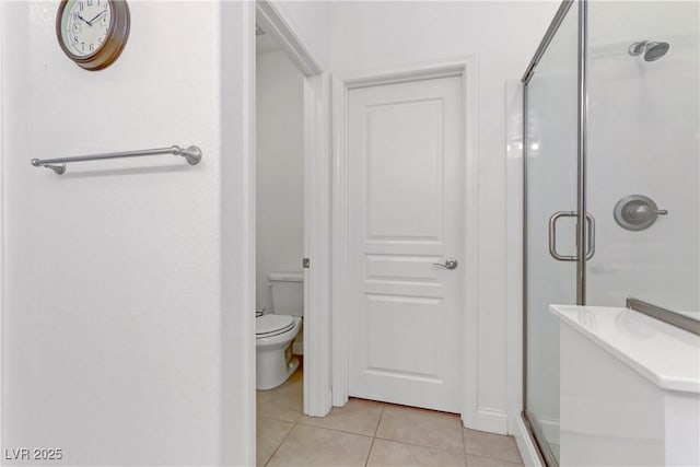 bathroom with toilet, a shower stall, and tile patterned flooring