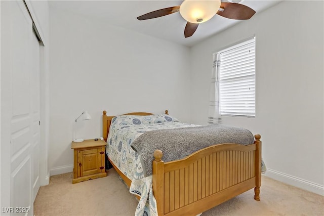 bedroom with a closet, baseboards, light colored carpet, and ceiling fan