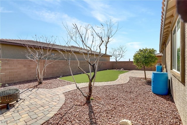 view of yard featuring a patio, a fenced backyard, and a fire pit