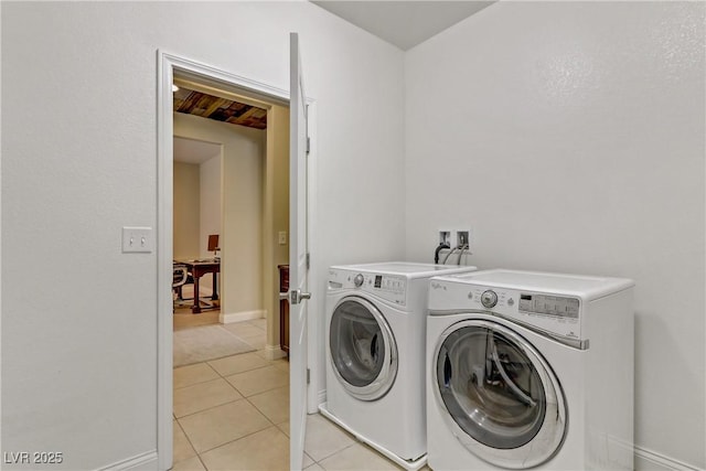 clothes washing area with washer and dryer, laundry area, light tile patterned flooring, and baseboards