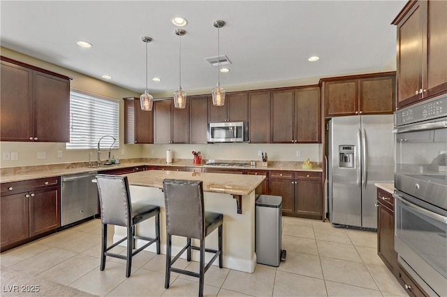 kitchen featuring visible vents, a sink, appliances with stainless steel finishes, pendant lighting, and a kitchen breakfast bar