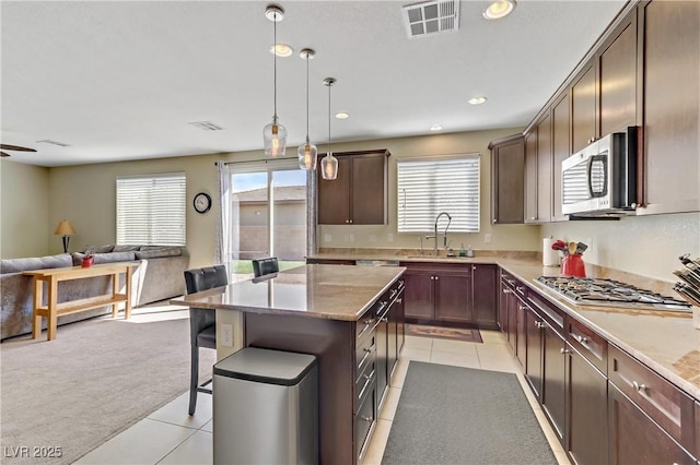 kitchen featuring a breakfast bar area, visible vents, a sink, stainless steel appliances, and open floor plan