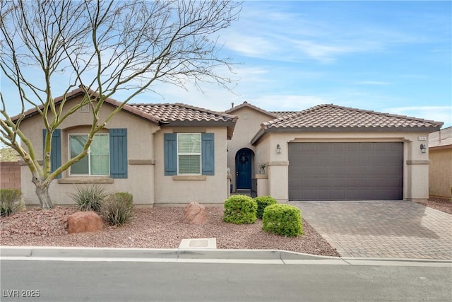 mediterranean / spanish-style house featuring a tiled roof, a garage, driveway, and stucco siding