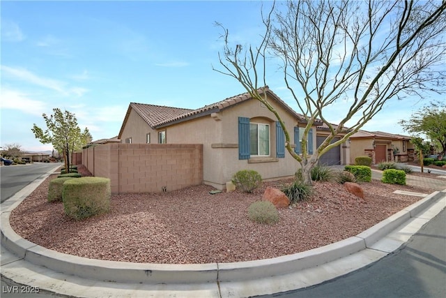 view of home's exterior with a tiled roof, fence, and stucco siding