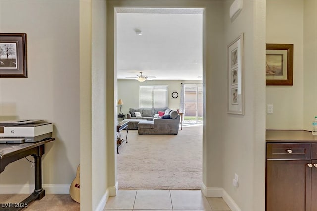 corridor featuring light carpet, light tile patterned floors, and baseboards