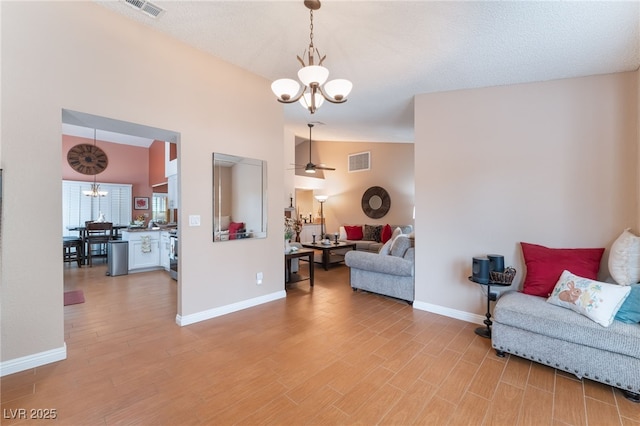 living area with vaulted ceiling, visible vents, and light wood finished floors